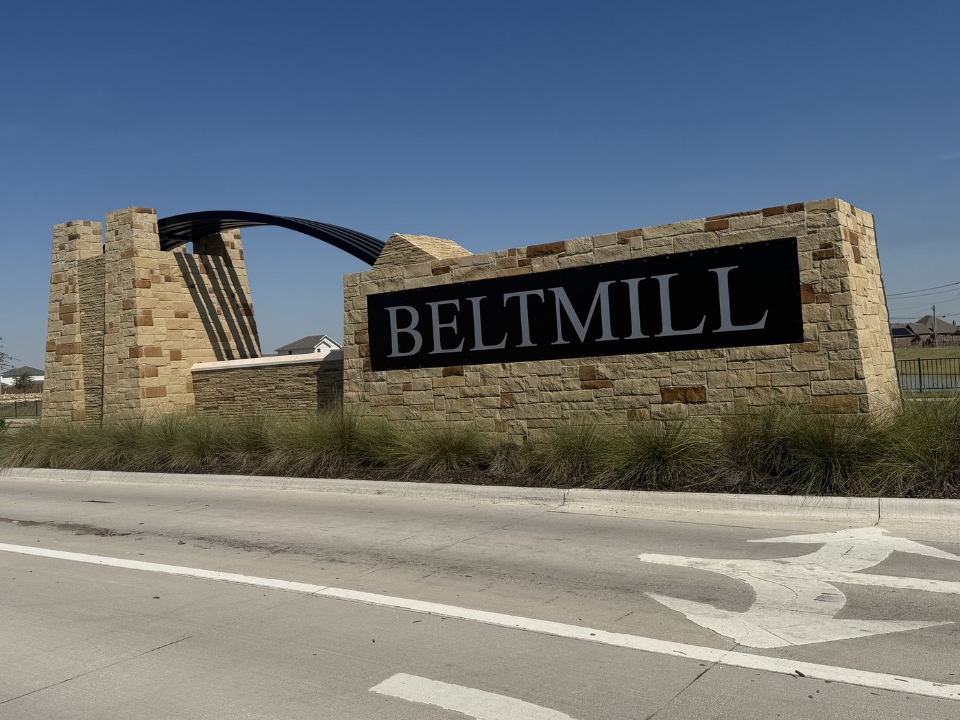 Stone entry monument with tapered stone towers and a steel arch in Saginaw