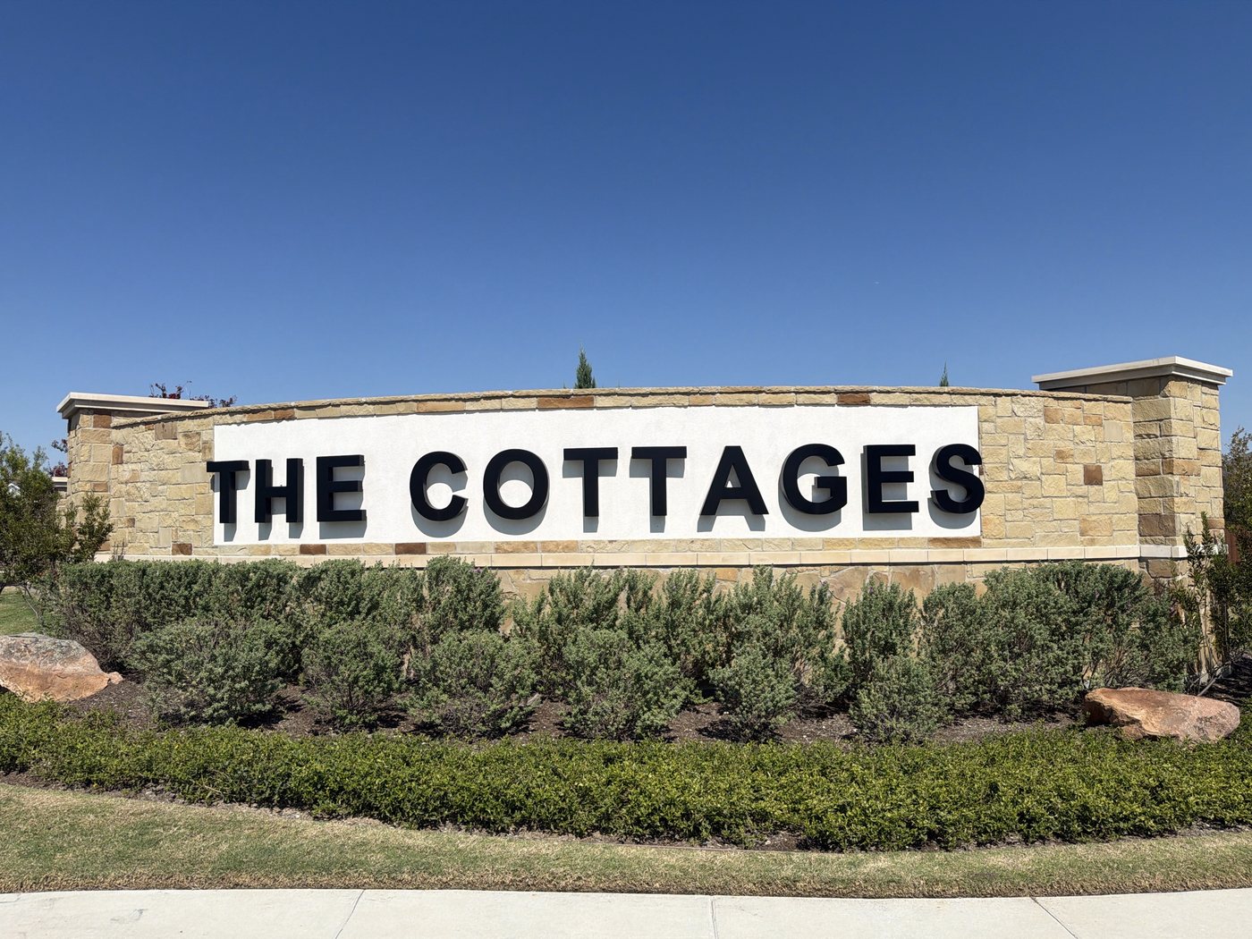 Curved stone sign wall with a stone column at each end, The Cottages at Beltmill, Saginaw