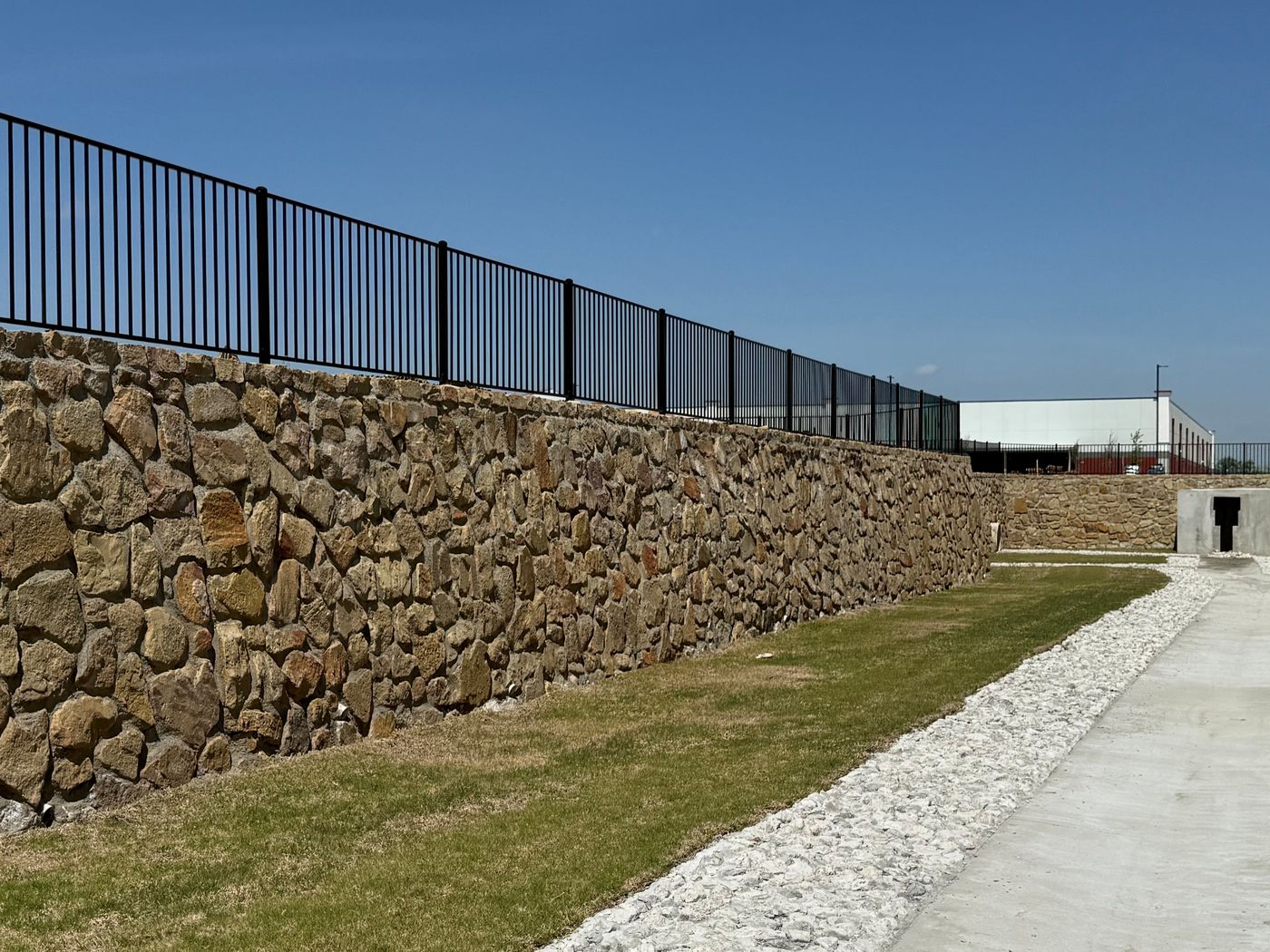 Stone wall with fence along a drainage channel, IKEA Ph 2, Grand Prairie