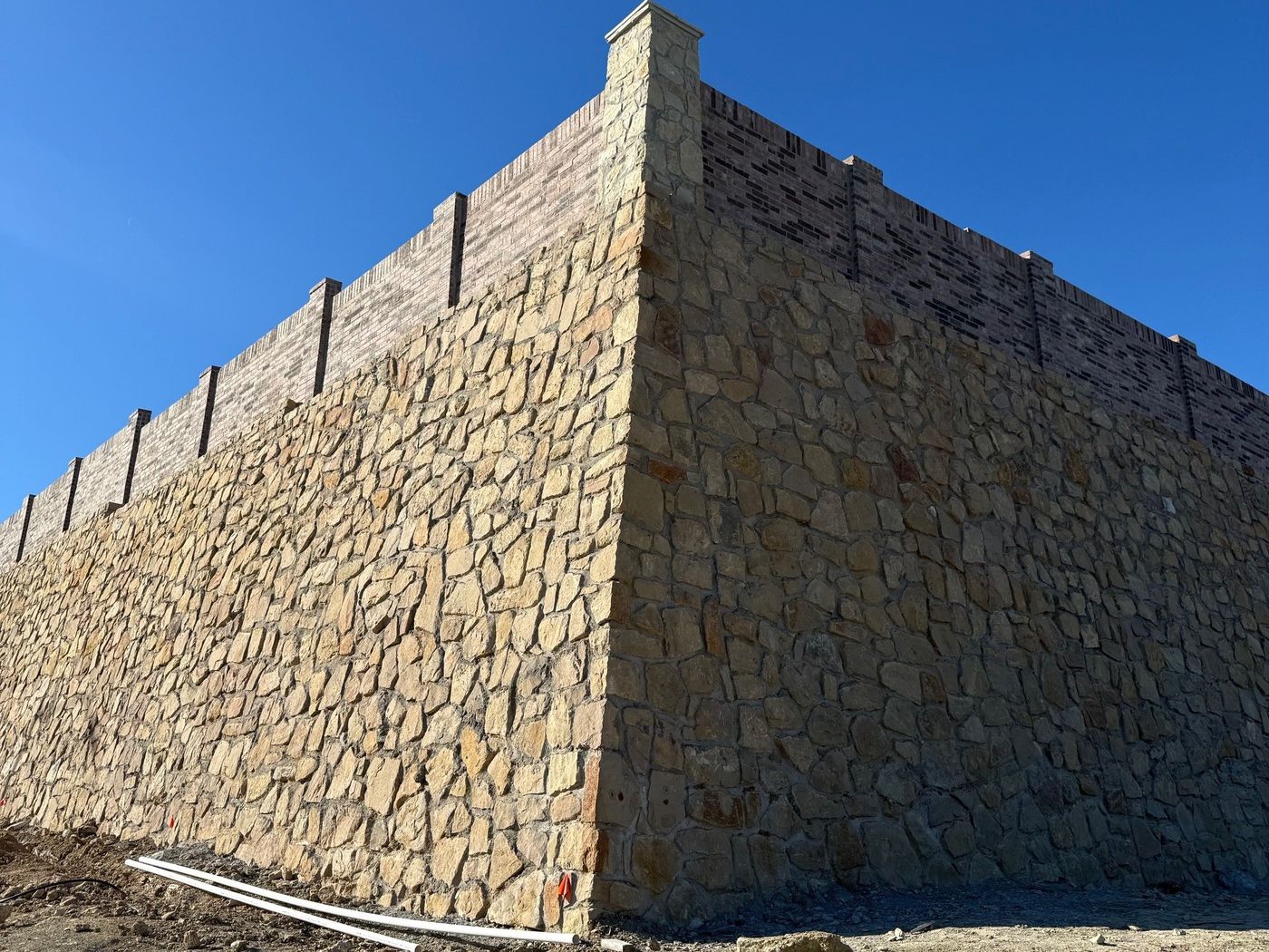 Stone retaining wall corner with column caps in Fort Worth
