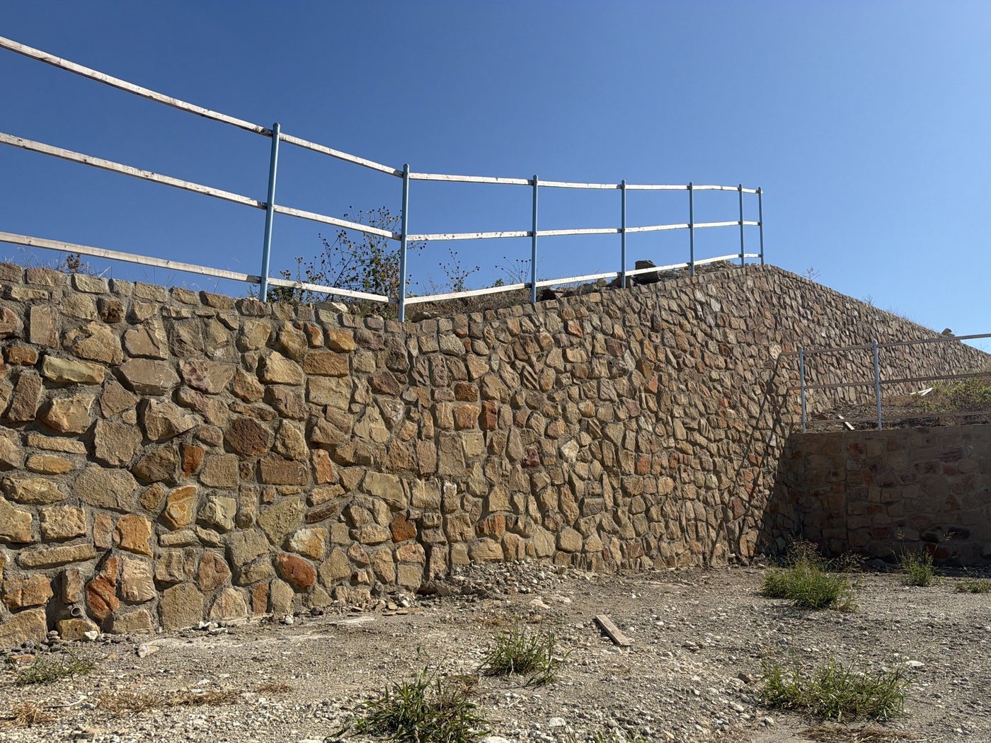 Stone wall rising with the slope at an inside corner, pipe rail on top, Northpointe West Ph 1B, Fort Worth